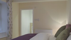 A bedroom with a bed, a radiator, and a window with curtains.