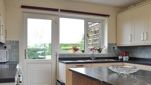 Een moderne keuken met een groot kookeiland, dubbele deuren en uitzicht op groen.