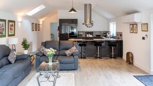 A modern living room with a sofa, coffee table, and a kitchen area with a bar. - 1 bedroom accommodation in Boughton, near Downham Market (Boughton, near Downham Market)