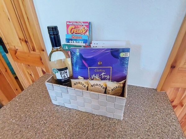 A gift basket containing a bottle of Bin 161 Pinot Grigio wine, a Cadbury Mk Tray chocolate box, and several Borde chocolate bars.