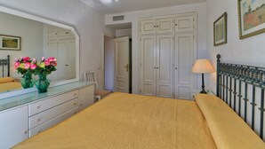 Ein Schlafzimmer mit einem Bett, einem Schminktisch, einem Spiegel, einer Lampe und einer Tür.