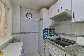 A kitchen with white cabinets, a clock on the wall, and a toaster on the counter.