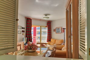 A living room with a sofa, a coffee table with a vase of flowers, and a dining area with a table and chairs.