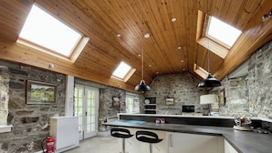 Une cuisine avec un mur en pierre, un plafond en bois et des fenêtres de toit.