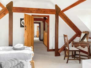 Ein Schlafzimmer mit einem Bett, einem Holzstuhl, einer Kommode und einer Tür zu einem anderen Raum.