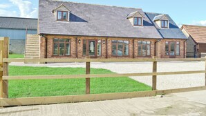 A two-story brick house with a sloped roof, multiple windows, and a wooden fence in the foreground. - The Granary - W43949 (East Tytherton, Chippenham)