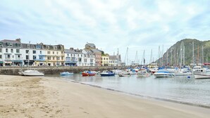 A beach with boats docked along the shore and buildings in the background. - 3 bedroom accommodation in Ilfracombe (Ilfracombe)
