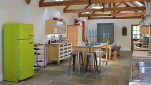 A kitchen with a green refrigerator, wooden beams, a dining area with stools, and a bar area.