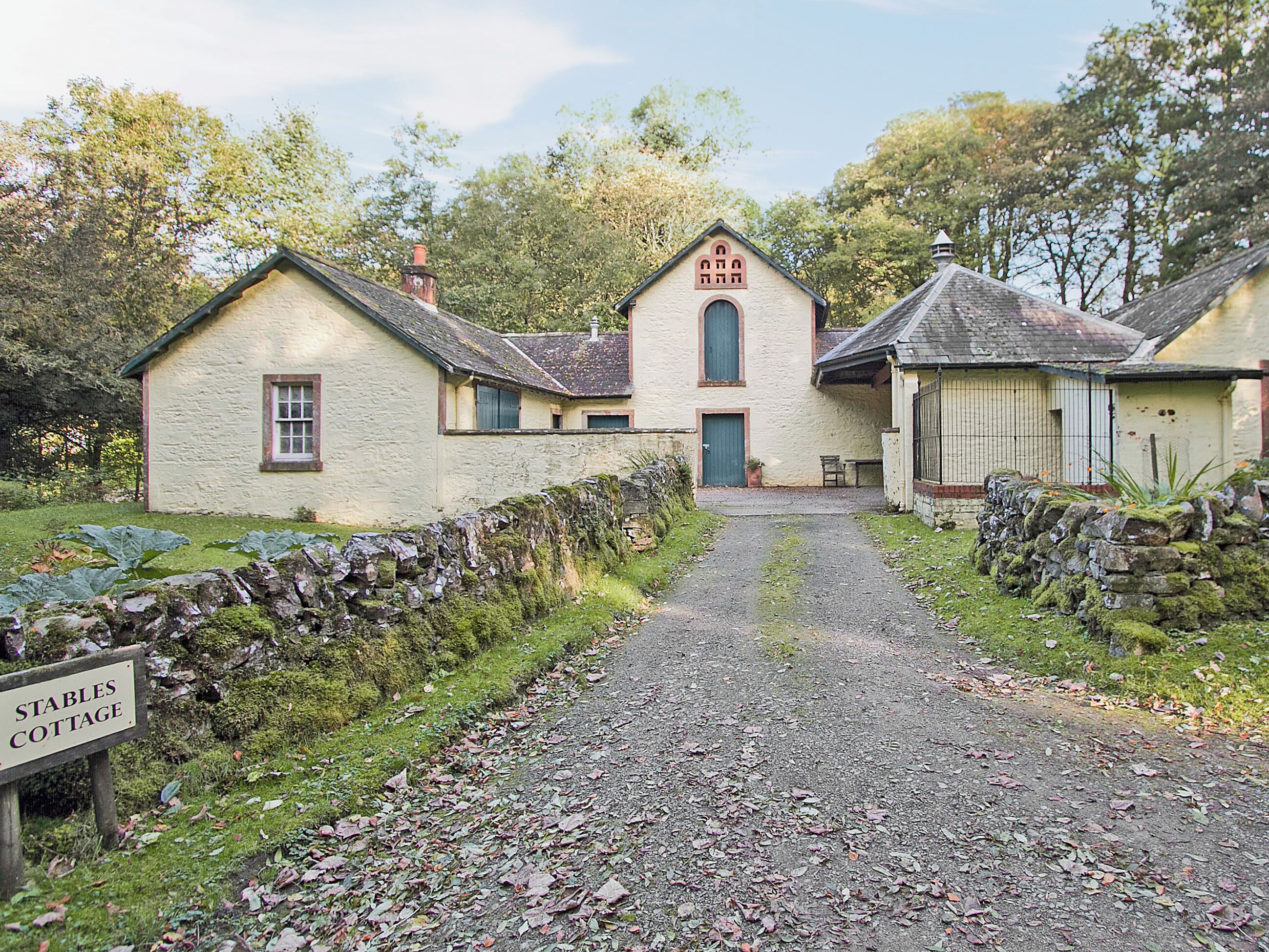 Une maison de campagne traditionnelle en pierre, avec une pancarte indiquant « Stables Cottage ».