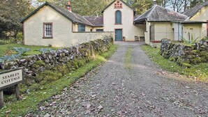 Una tradicional cabaña de piedra con un letrero que dice 'Stables Cottage'.