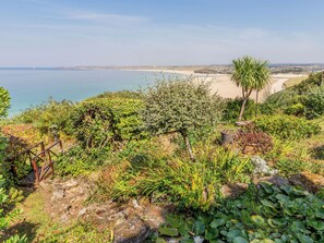 Eine Küstenlandschaft mit vielfältiger Vegetation, einem Sandstrand und freiem Blick auf das Meer.