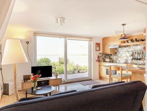 Ein modernes Wohnzimmer mit Sofa, Fernseher und Essbereich mit Tisch und Stühlen.