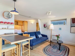 Ein gemütlicher Wohnbereich mit einem blauen Sofa, einem Holzesstisch und einem runden Teppich.