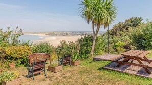 Un patio con panche di legno e tavolo da picnic con vista sulla spiaggia.