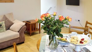 En stue med sofa, sofabord med blomster og et bord med mad og drikke.