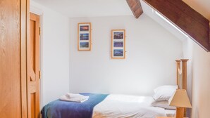 Una camera da letto con un letto, un comodino, una lampada e due quadri appesi al muro.