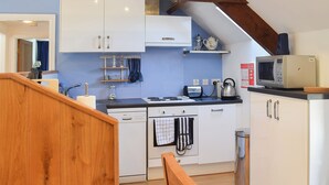 Una cucina compatta con mobili bianchi, una lavastoviglie Bosch, un bollitore e un forno a microonde.