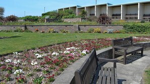 A garden with benches and a building with multiple rooms in the background. - 2 bedroom accommodation in Sheringham (Sheringham)
