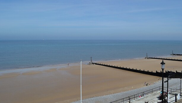 A beach with a sandy shore, a promenade, and a sign indicating facilities like toilets and a children's play area. - 2 bedroom accommodation in Sheringham (Sheringham)