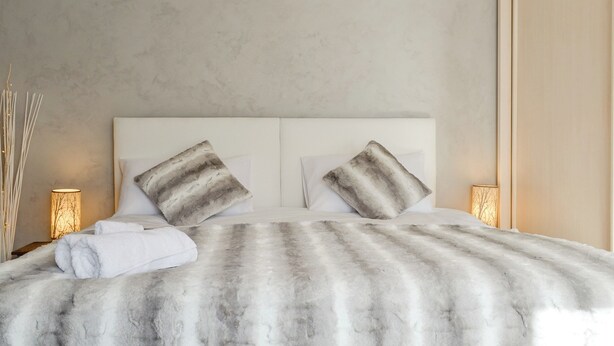 Una cama con un edredón a rayas, dos almohadas y una lámpara de noche.