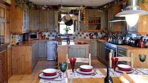 Una cocina con armarios de madera, una isla central y un comedor con platos rojos y blancos.