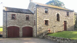 Un edificio de piedra con dos grandes puertas de madera y una ventana pequeña.
