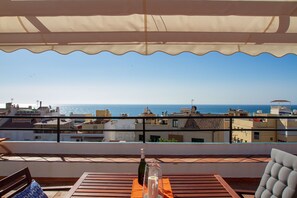 A terrace with a view of the sea, a bottle of champagne, and a glass on a table.
