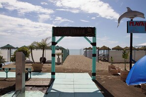 A beach entrance with a sign, a lifeguard tower, and beach huts. - Silvia | Rooftop Terrace, Sea View & Beach (Torremolinos)
