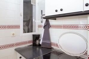 A kitchen with white tiled walls, a window with blinds, a coffee maker, and a towel hanging on the rack. - Silvia | Rooftop Terrace, Sea View & Beach (Torremolinos)