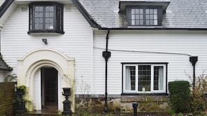 A white building with a pitched roof, a central entrance with an arch, and two windows with shutters. - 2 bedroom accommodation in Llanddona, near Beaumaris (Llanddona, near Beaumaris)