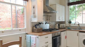 A kitchen with white cabinets, a gas stove, a toaster, and a washing machine.