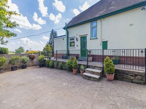 A house with a green door, a small porch, and a stone wall.