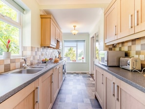Una cocina moderna con armarios de madera, encimera de granito, un lavabo, microondas y tostadora.
