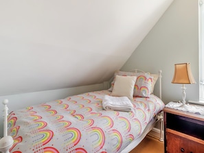 Un dormitorio con cama, almohadas, una mesita de noche, lámpara y cómoda.