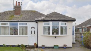 A two-story house with a white exterior, a front door, and a small garden area with potted plants.