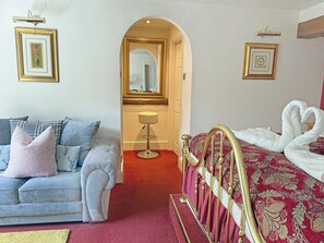 A bedroom with a bed, a sofa, a mirror, and framed pictures on the walls.