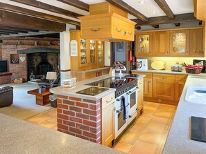 Una cocina con gabinetes de madera, una isla de ladrillo, una estufa y una chimenea.