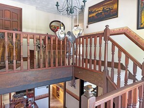 Una escalera de madera con candelabro, espejo y obras de arte en las paredes.