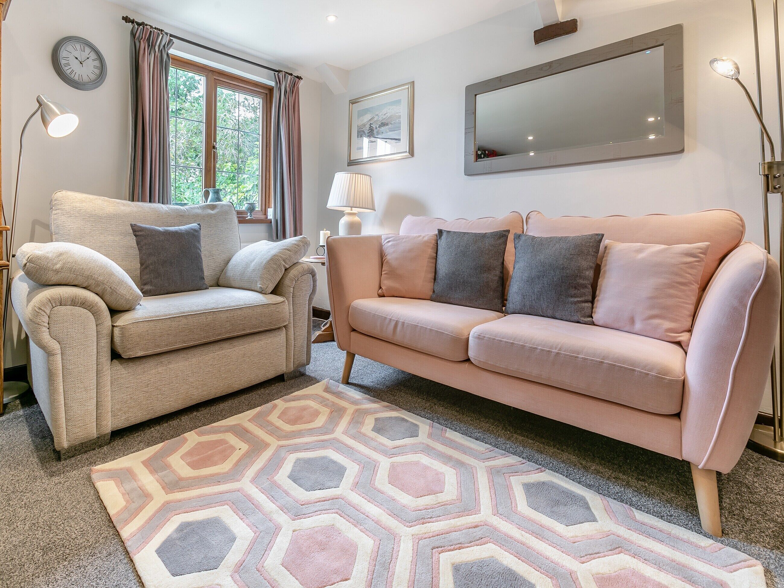 A living room with a beige armchair, a pink sofa, and a patterned rug.