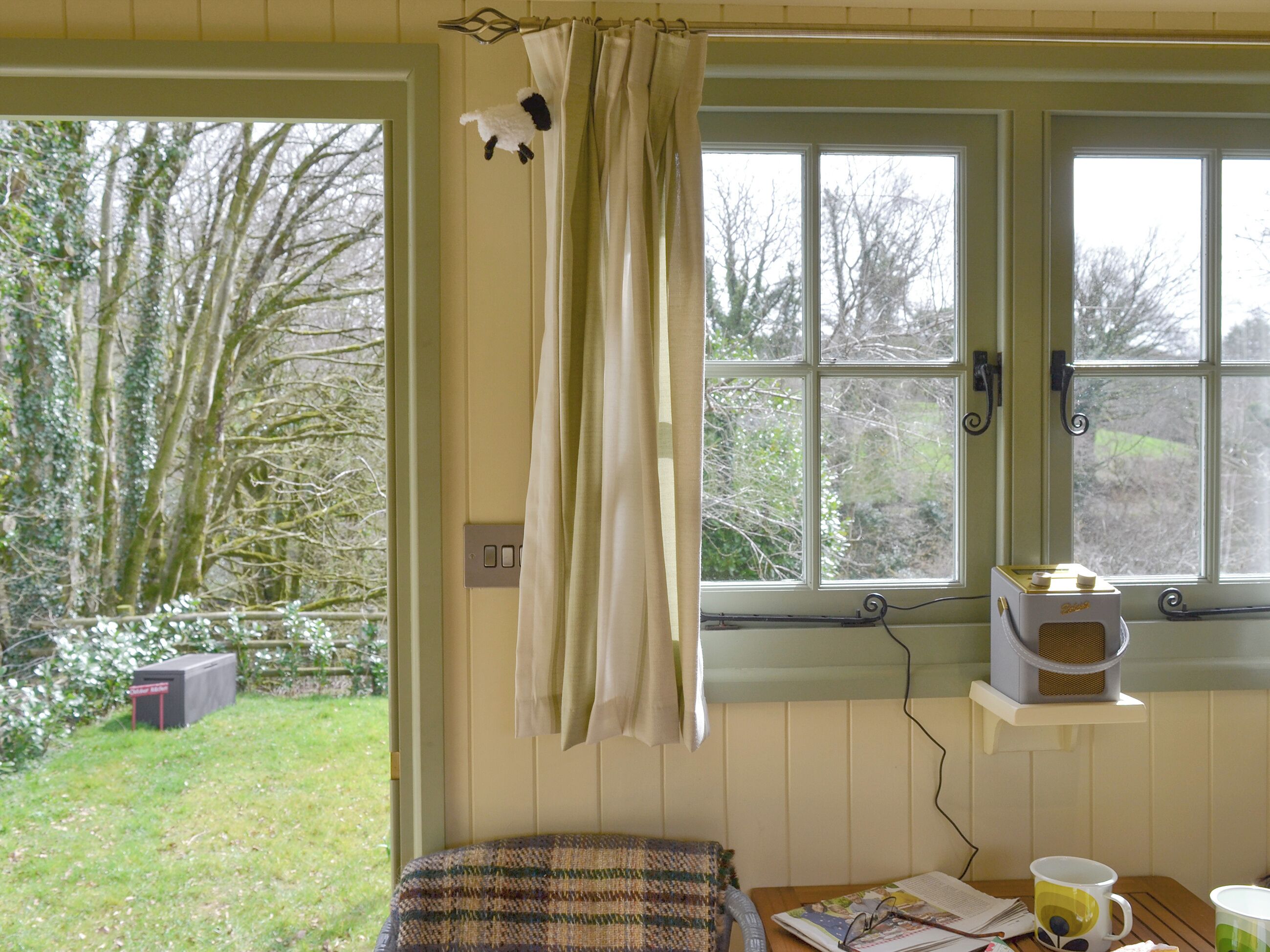 A room with a window, a small table with a cup, and a chair.