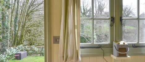 A room with a window, a small table with a cup, and a chair.