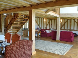 A spacious room with a wooden staircase, a red patterned sofa, and a large rug on the floor.
