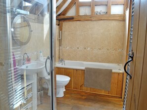 Un baño con cabina de ducha de vidrio, lavamanos, inodoro y bañera de madera.