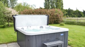 Ett bubbelbad med en bänk, omgivet av en gräsyta och träd.