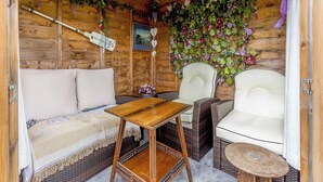 Een knus houten blokhut interieur met een bank, twee stoelen, een bijzettafeltje en sierplanten.