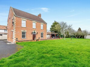 A two-story brick house with a well-maintained lawn and a covered outdoor seating area.