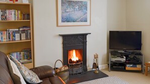 Ein Wohnzimmer mit Kamin, Bücherregal, Fernseher und einer Couch.