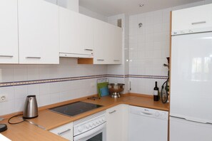 A modern kitchen with white cabinetry, a stainless steel kettle, a wine bottle, and a dishwasher.