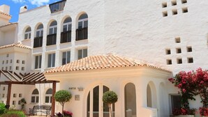 A white building with arched windows and a tiled roof, a sign reading "PORTAL 1", and potted plants in the foreground. - Puerta del Mar - Direct access to the beach (Mijas Costa)