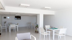 A spacious, well-lit meeting room with white furniture, a flat-screen TV, and ceiling lights. - Puerta del Mar - Direct access to the beach (Mijas Costa)